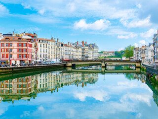Les quais de la Nive à Bayonne, leurs façades colorées et un pont, reflétés dans l'eau