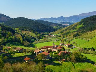 Village aux toits rouges et son église au creux d'une vallée verdoyante