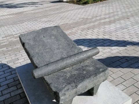 Pierre à broyer le cacao et son rouleau, exposée sur un socle en plein air